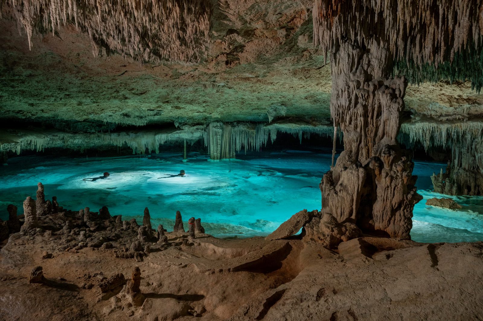 Divers exploring an underground cenote cave system near the Yucatan