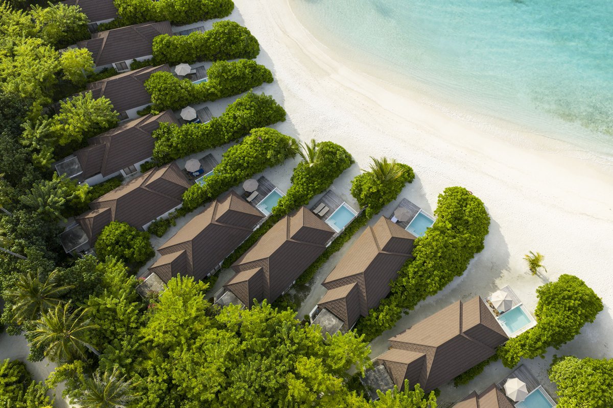 Row of beach villas with private plunge pools beside the sand