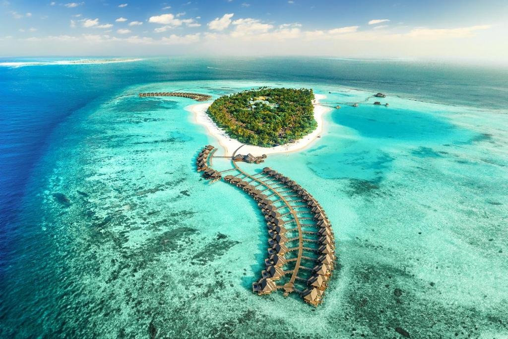 Aerial view of a Maldives resort island surrounded by reef and overwater villas